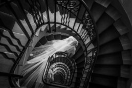 Photo en noir et blanc d'une mariée descendant les escaliers de chez elle