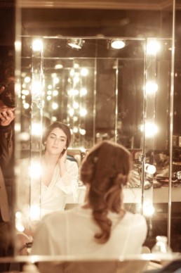 Une mariée qui contemple à travers un miroir pendant les préparatifs de son mariage
