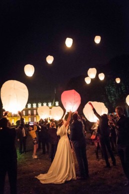 photo reportage des mariés lançant une lanterne dans le ciel entouré de leurs invités