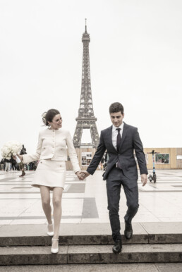 Couple de mariés marchant devant la tour Eiffel à Paris.