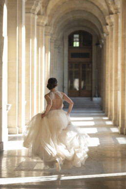 Mariée courant dans un long couloir aux arches élégantes.