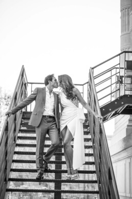 Couple de mariés s’embrassant sur un escalier métallique.