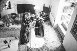 Demoiselles d’honneur entourant la mariée pour ajuster sa robe.