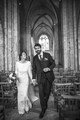 Mariés marchant dans l’allée d’une église après la cérémonie.