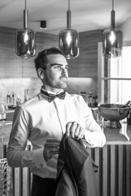 Le marié en chemise et nœud papillon dans la cuisine.