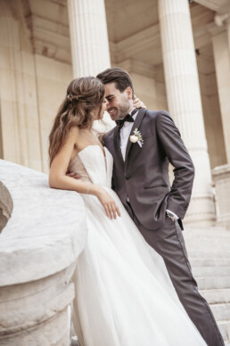Les mariés s’enlacent devant des colonnes.
