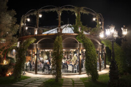 Invités d’un mariage dînant dans un pavillon vitré la nuit.