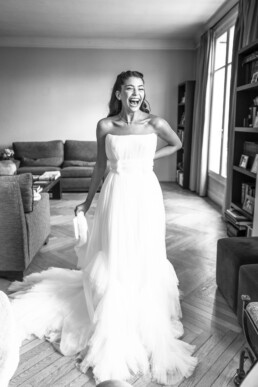 Mariée riant en robe de mariée dans un salon lumineux.