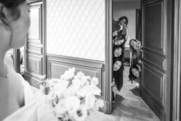 Demoiselles d’honneur regardant la mariée depuis une porte entrouverte.