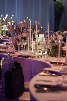 Table de mariage décorée de fleurs, verres et bougies allumées.