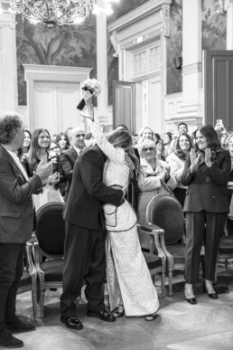 Les mariés s’embrassent devant leurs invités qui applaudissent.