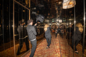 wedding photography assistant holding a softbox light in a dark mirrored venue while the photographer works